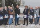 Blake Hairston (center left), Master of San Andres Lodge in Cameron receives the commemorative footstone from Raborn Reader (center right), Grand Master of Masons in Texas, flanked by local Masons and Grand Lodge officers with the backdrop of the monument