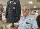 Jekel stands next to his own military uniform, which is also part of the display.